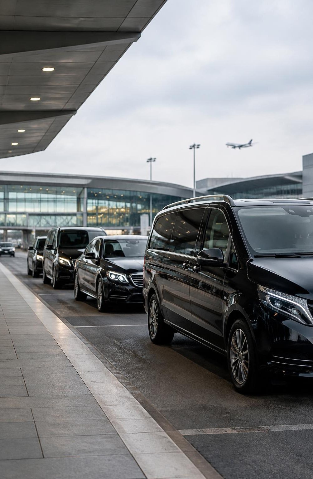 A row of executive cars and people carriers at an airport pick-up kerb
